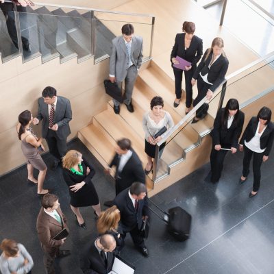 Business people in suits mingling in lobby signifying role-based training Business people in suits mingling in lobby signifying role-based training